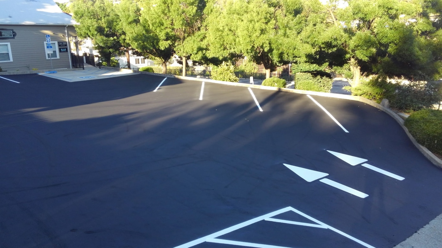Freshly sealcoated commercial parking lot with line striping and directional arrows — Amador County